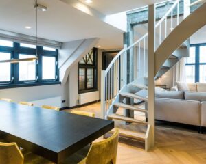 Moderne kantoorruimte aan de Westermarkt 2 in Amsterdam met een open indeling, houten vloer, eettafel, draaiende trap en comfortabele zithoek.