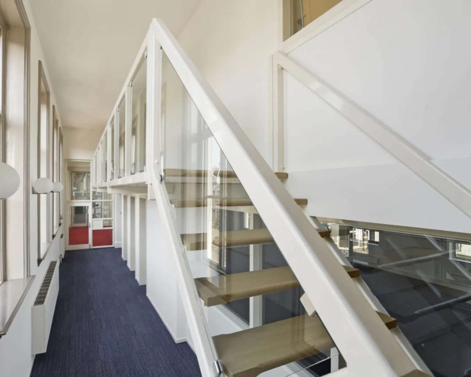 Moderne kantoorruimte met glazen balustrade en houten trap aan de Wilhelminastraat 43A in Haarlem.