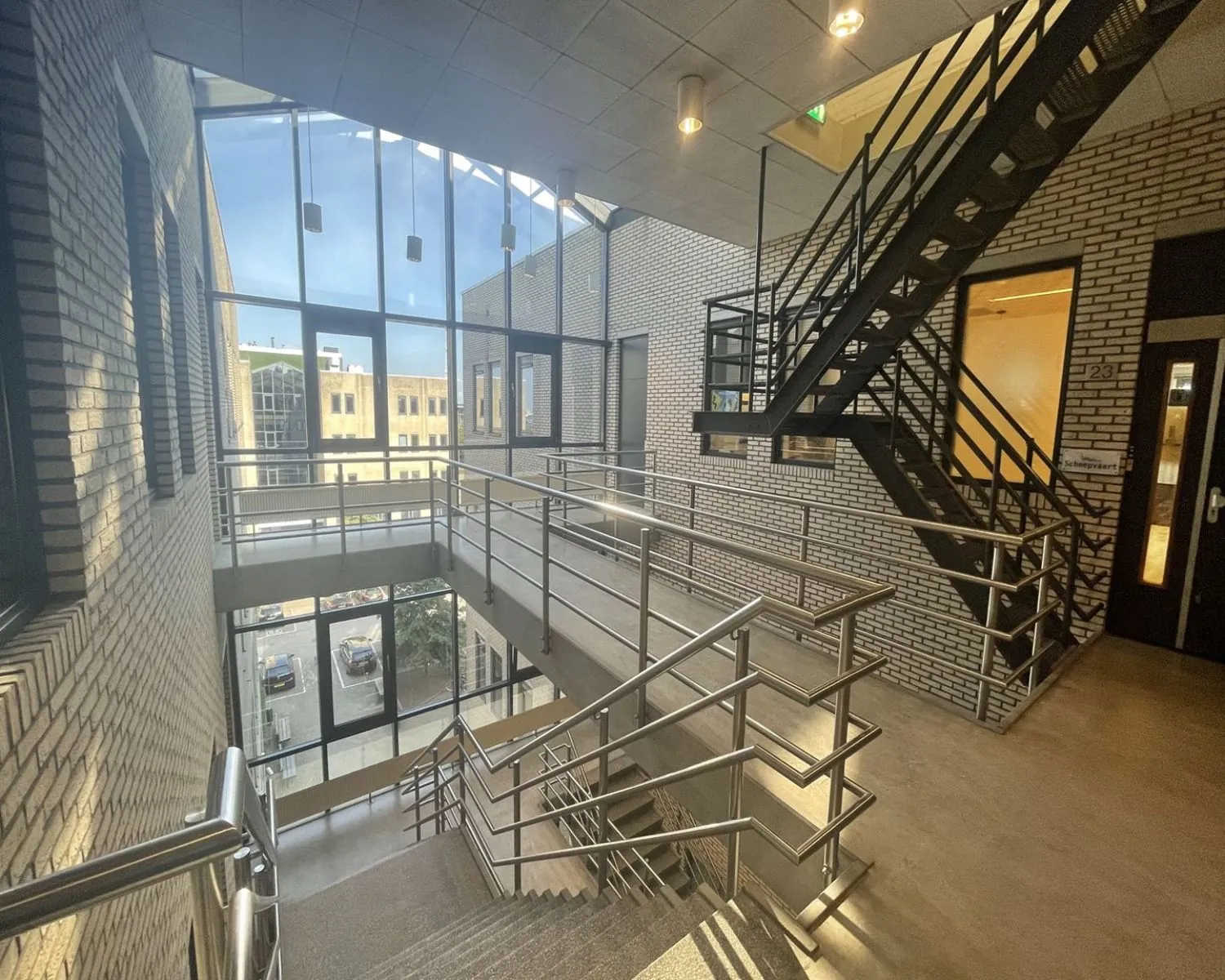 Trapportaal met grote ramen en metalen trappen in een modern kantoorgebouw aan de Zekeringstraat 17 in Amsterdam.