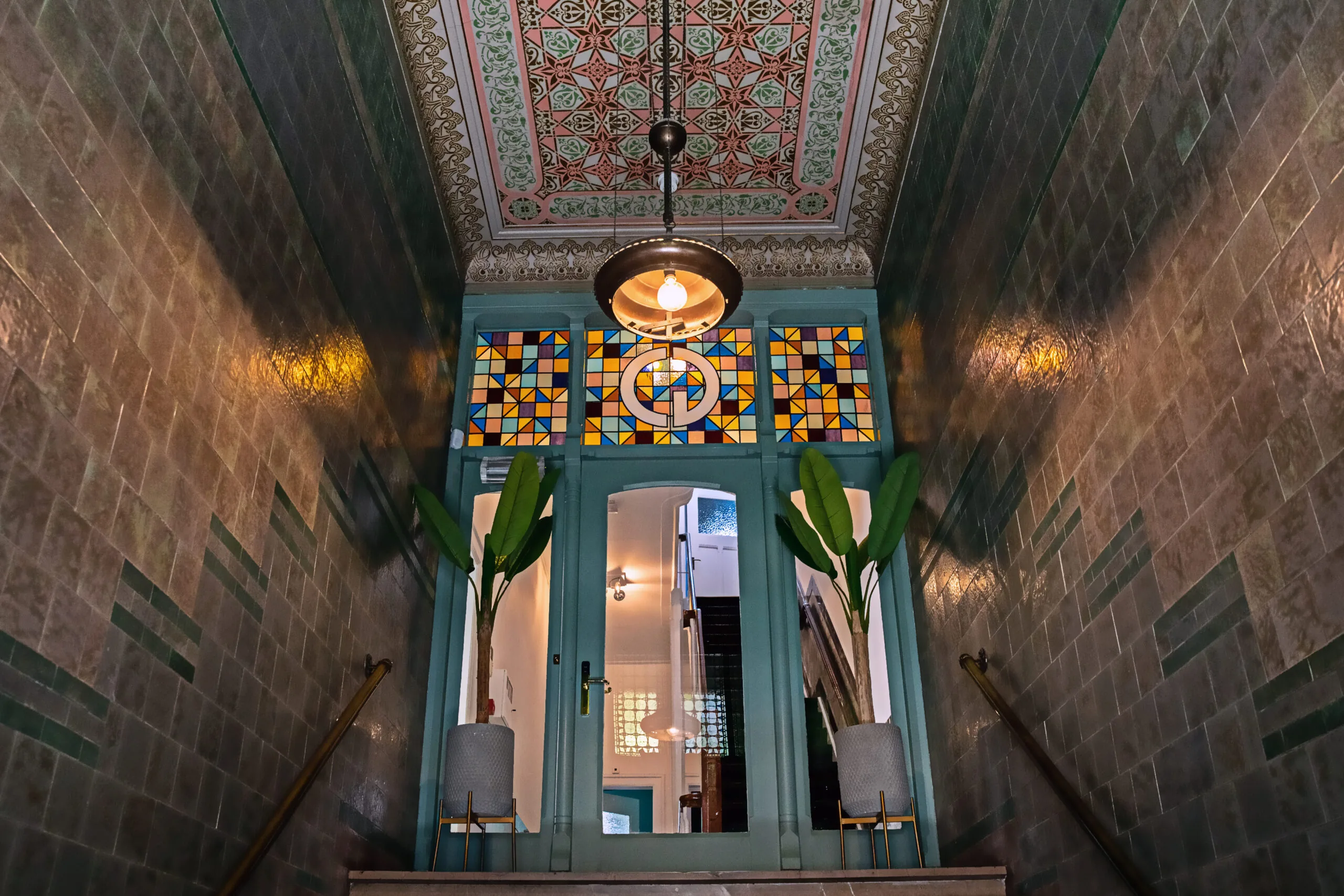 Ingang van Creativegrounds – Emmalaan met kleurrijk glas-in-lood, planten en rijk gedecoreerd plafond.