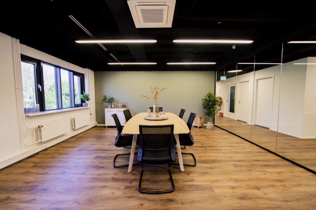 Vergaderruimte met een houten tafel, zes stoelen en decoratieve planten in het ELE Office in Woerden.