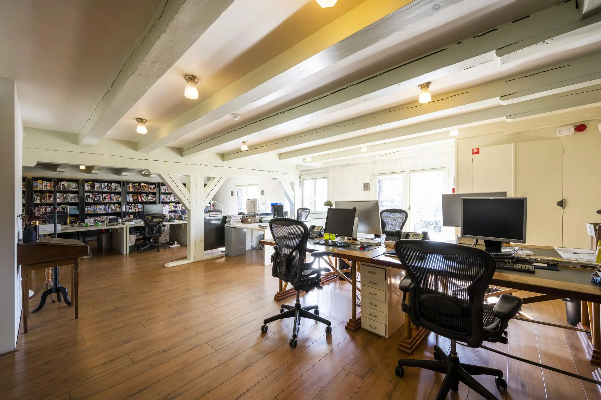 Ruim en licht kantoor aan de Leidsegracht met houten vloer, zichtbare balken en meerdere werkplekken met computers.