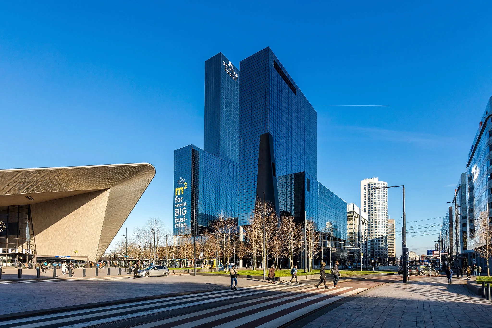 Straatbeeld van het Weena in Rotterdam met het moderne gebouw van Delftse Poort en het naastgelegen Centraal Station.