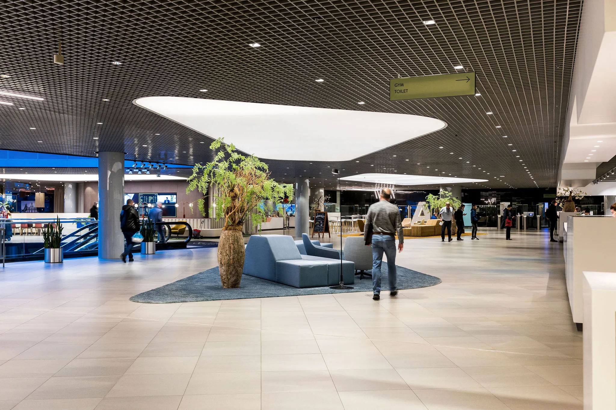 Moderne kantoorlobby aan het Weena met zitgelegenheid, planten en mensen in een open ruimte.