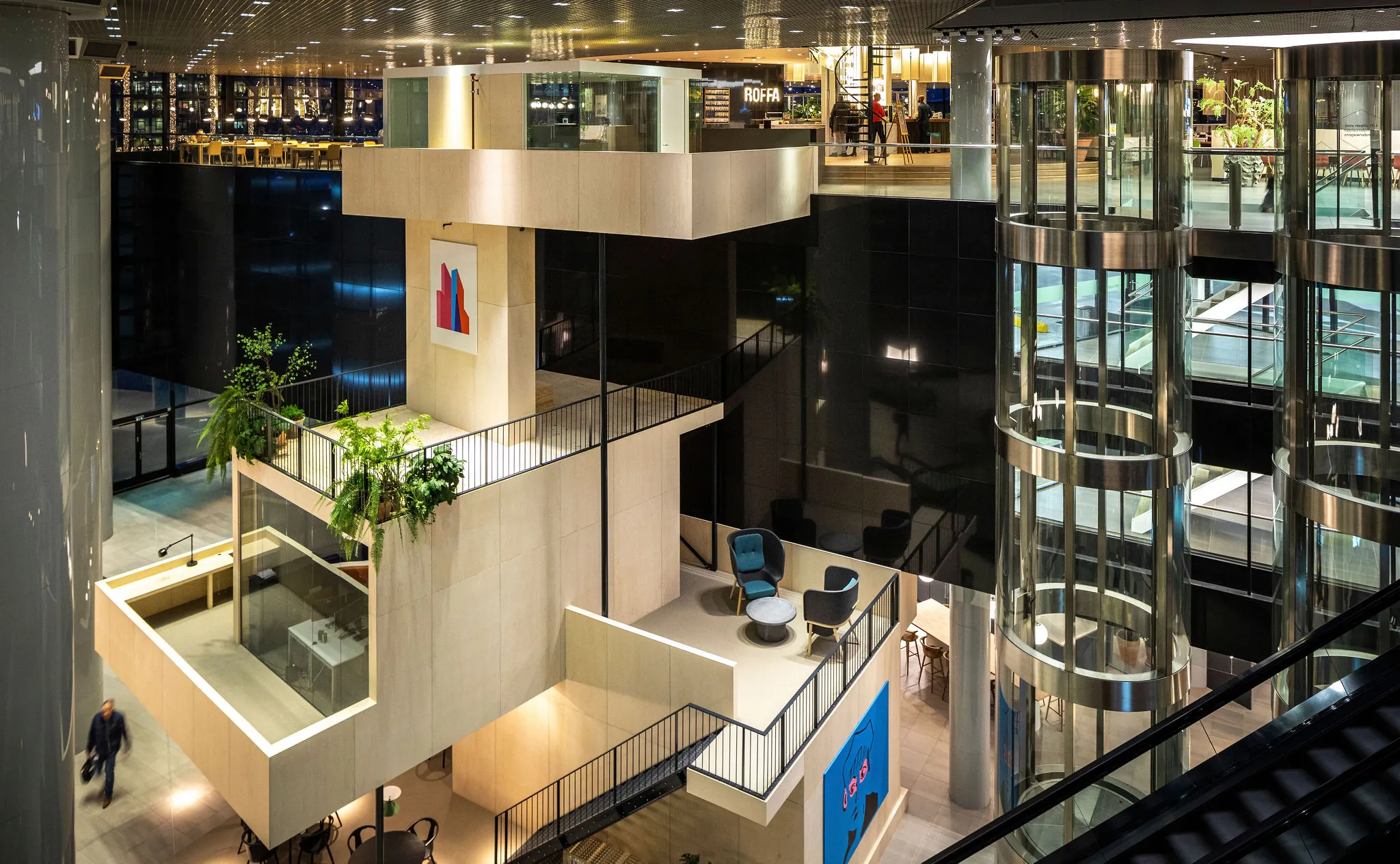 Modern kantoorgebouw aan het Weena met meerdere verdiepingen, glazen liften en groene accenten in het interieur.