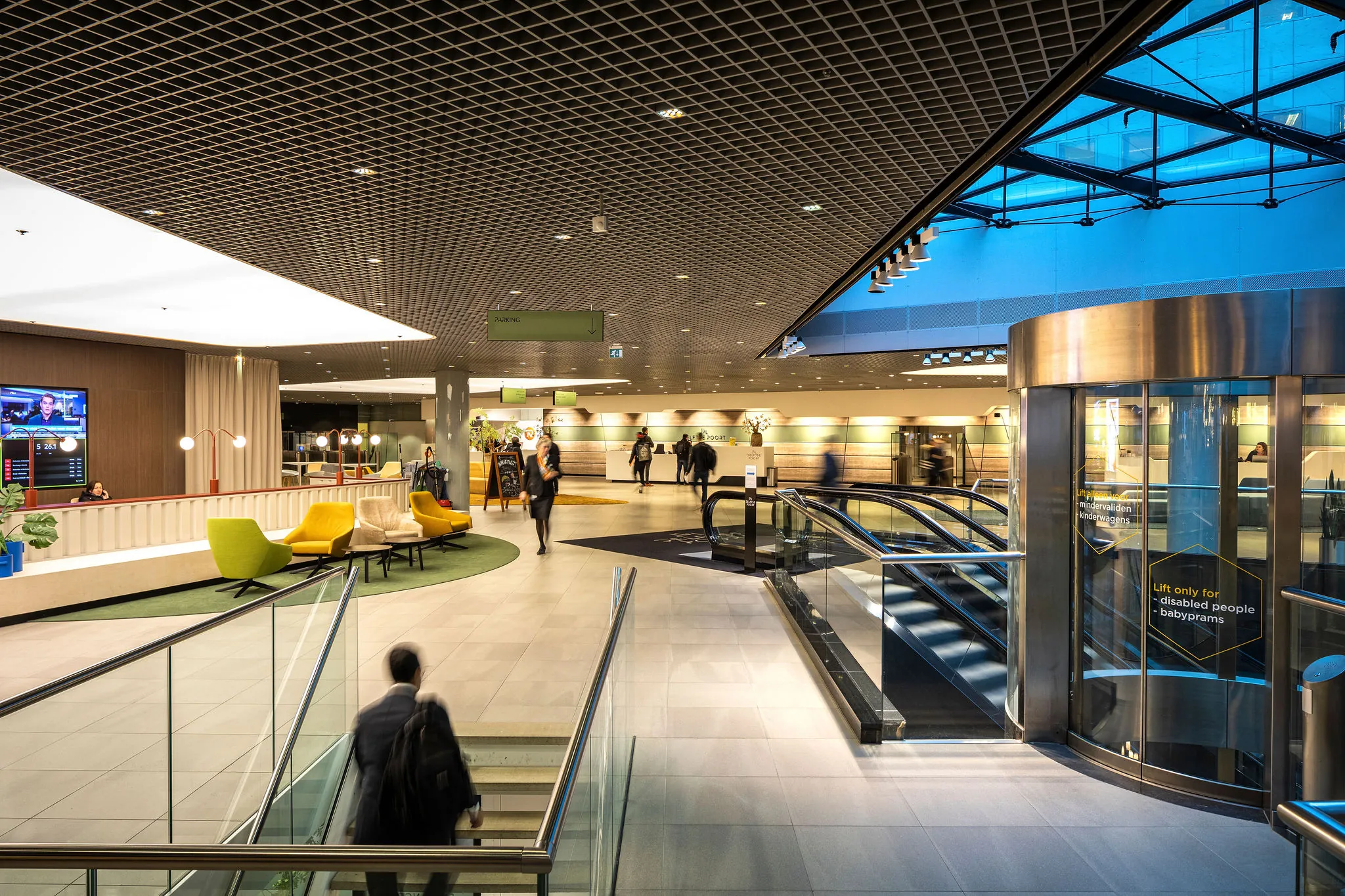 Moderne en kleurrijke lobby van een kantoorgebouw aan het Weena met roltrappen, zitgedeelte en receptie.