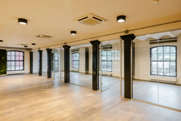 Een lege, moderne kantoorruimte met houten vloer en glazen wanden.