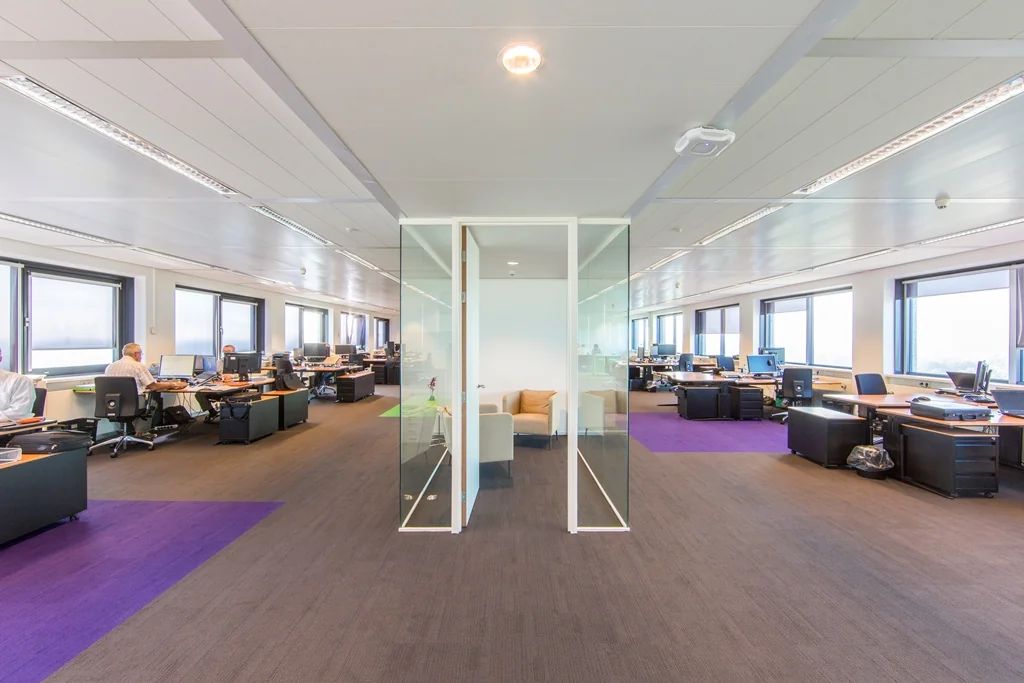 Modern open kantoorinterieur aan de Nevelgaarde met ruime bureaus, glazen vergaderruimte en grote ramen.