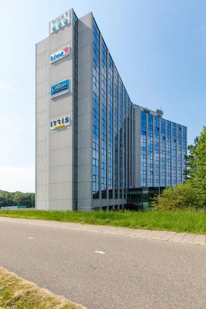 Modern kantoorgebouw aan de Nevelgaarde met logo’s van bedrijven zoals Triple P, Kiwa, Colliers International en IT RIS.
