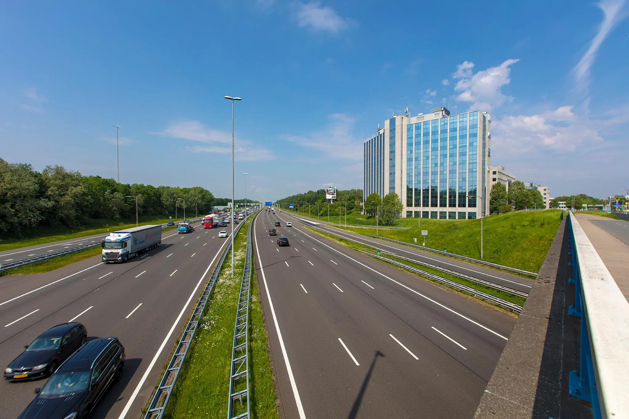 Drukke snelweg bij kantoorgebouw Nevelgaarde in Utrecht op een zonnige dag.