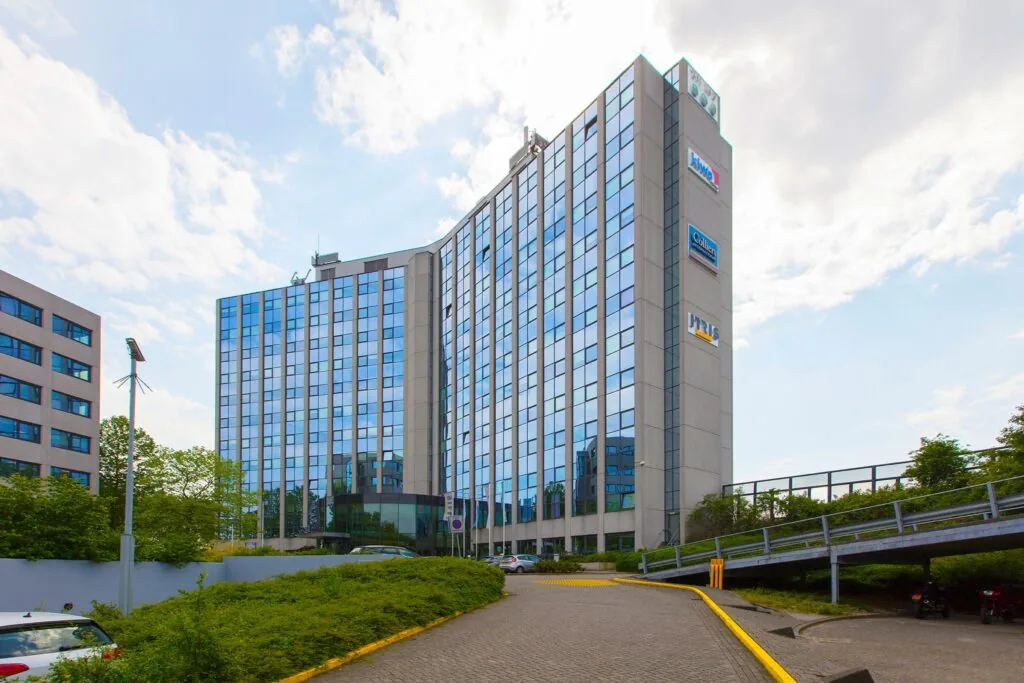 Een modern kantoorgebouw aan de Nevelgaarde met spiegelende ramen en meerdere bedrijfslogo’s op de gevel.