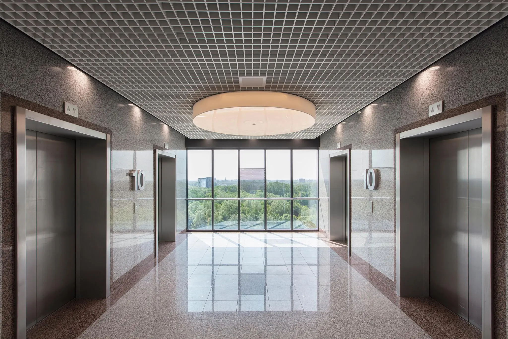 Moderne liftlobby op de tiende verdieping van kantoorgebouw Nevelgaarde met uitzicht op een groene omgeving.