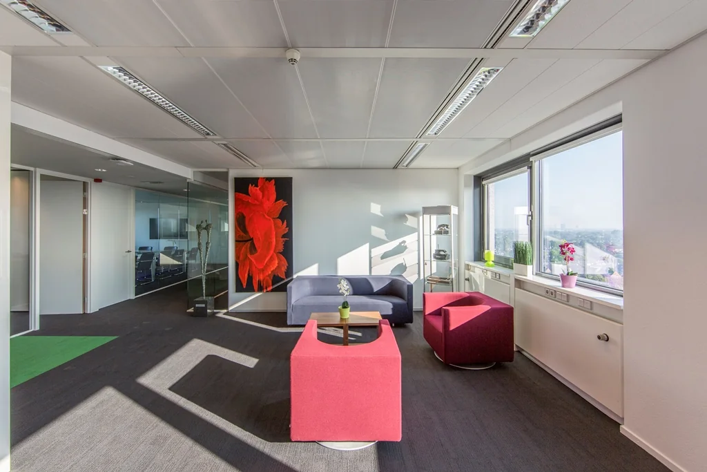 Moderne wachtruimte in kantoor Nevelgaarde met kleurrijke stoelen, kunst aan de muur en uitzicht door grote ramen.