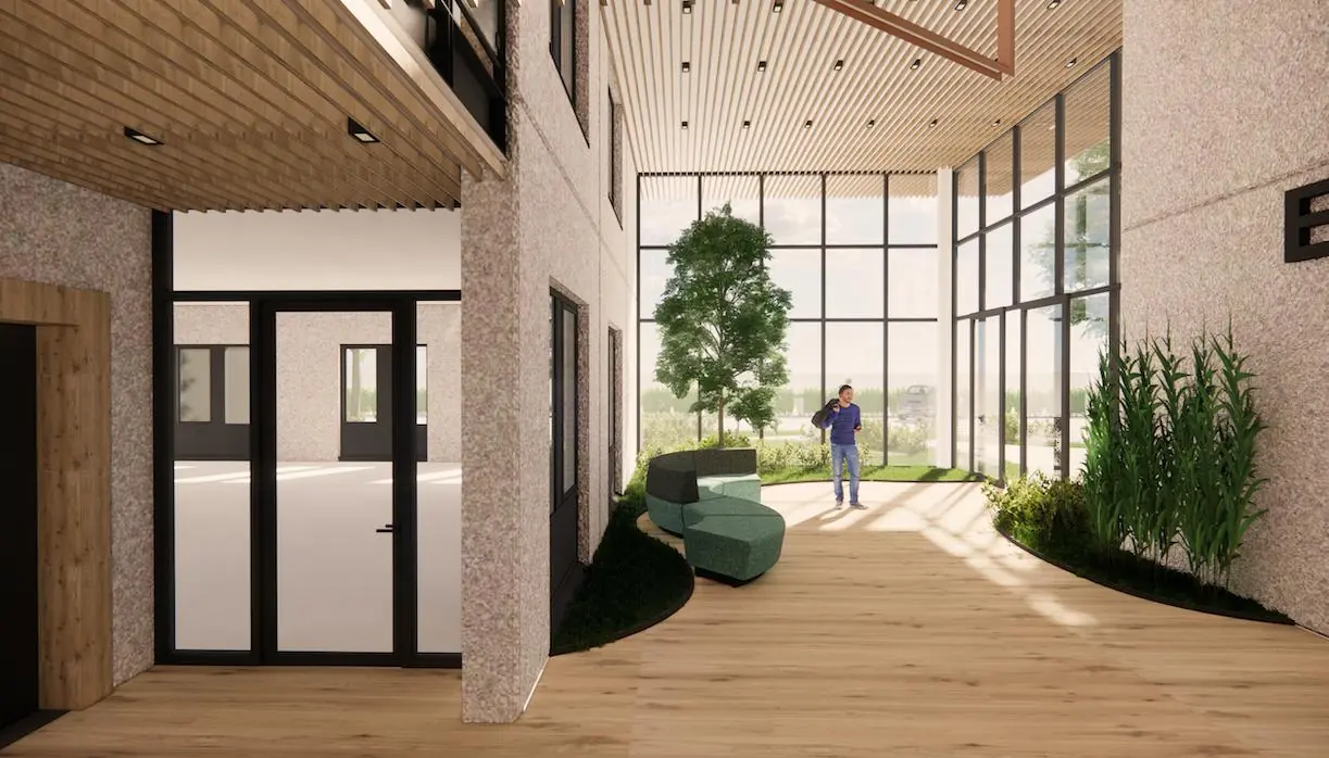 Lichte en moderne entreehal van Rijnzathe met houten vloer, grote raampartijen en groenvoorziening.