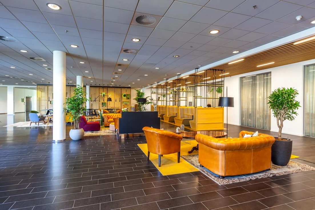 Moderne, kleurrijke lounge- en werkruimte met leren fauteuils en houten zitnissen aan de Orteliuslaan.