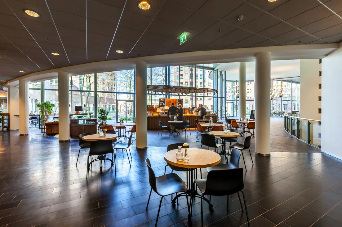 Moderne en lichte horecaruimte met zitplaatsen en een koffiebar in het gebouw aan de Orteliuslaan.