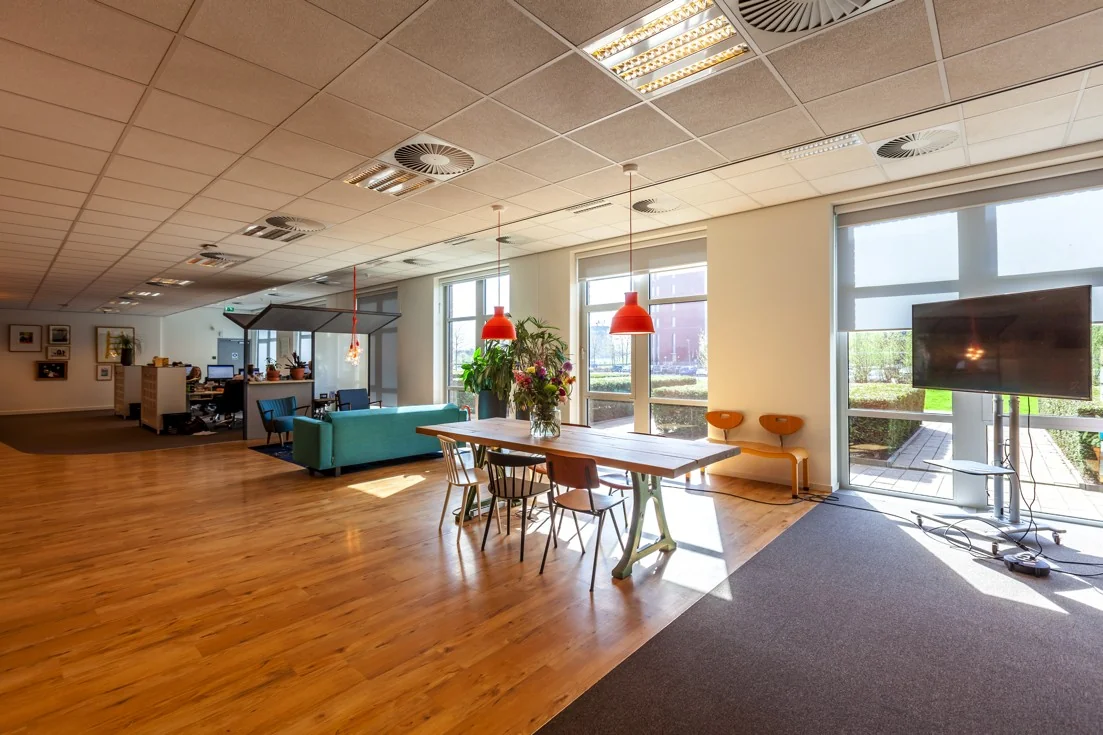 Moderne, lichte kantoorruimte aan de Orteliuslaan met een vergadertafel, zitgedeelte, planten en een groot beeldscherm bij het raam.