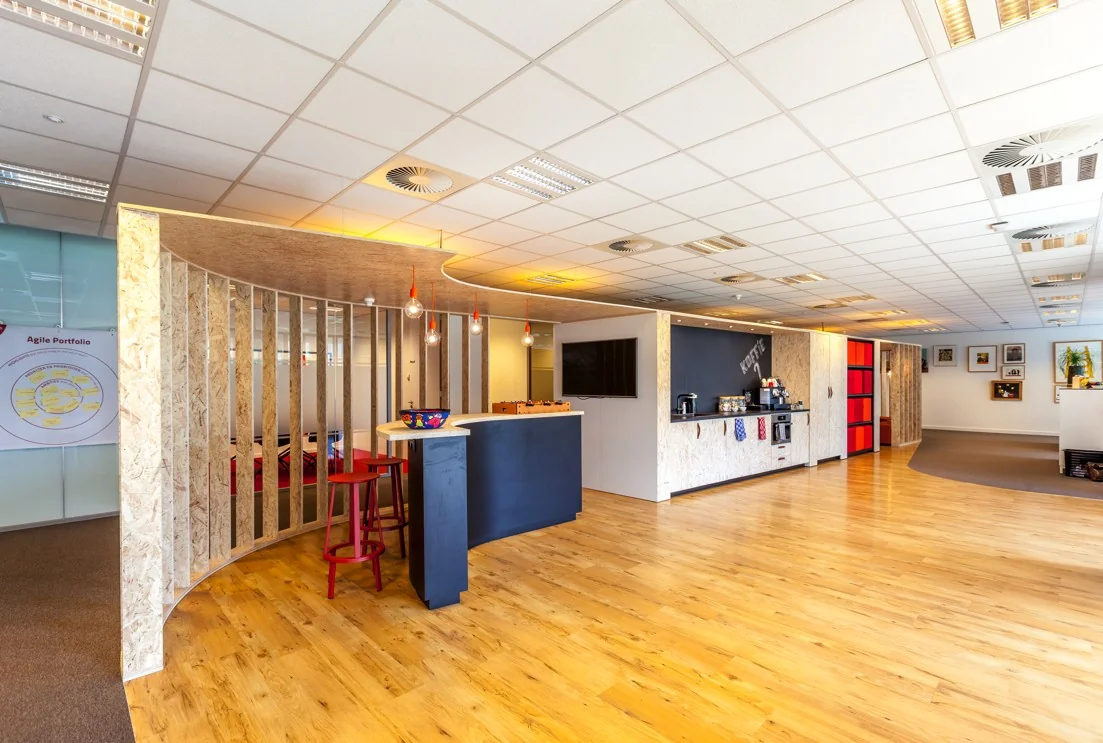 Moderne kantoorruimte aan de Orteliuslaan met een open koffiehoek, zithoek en houten vloer.
