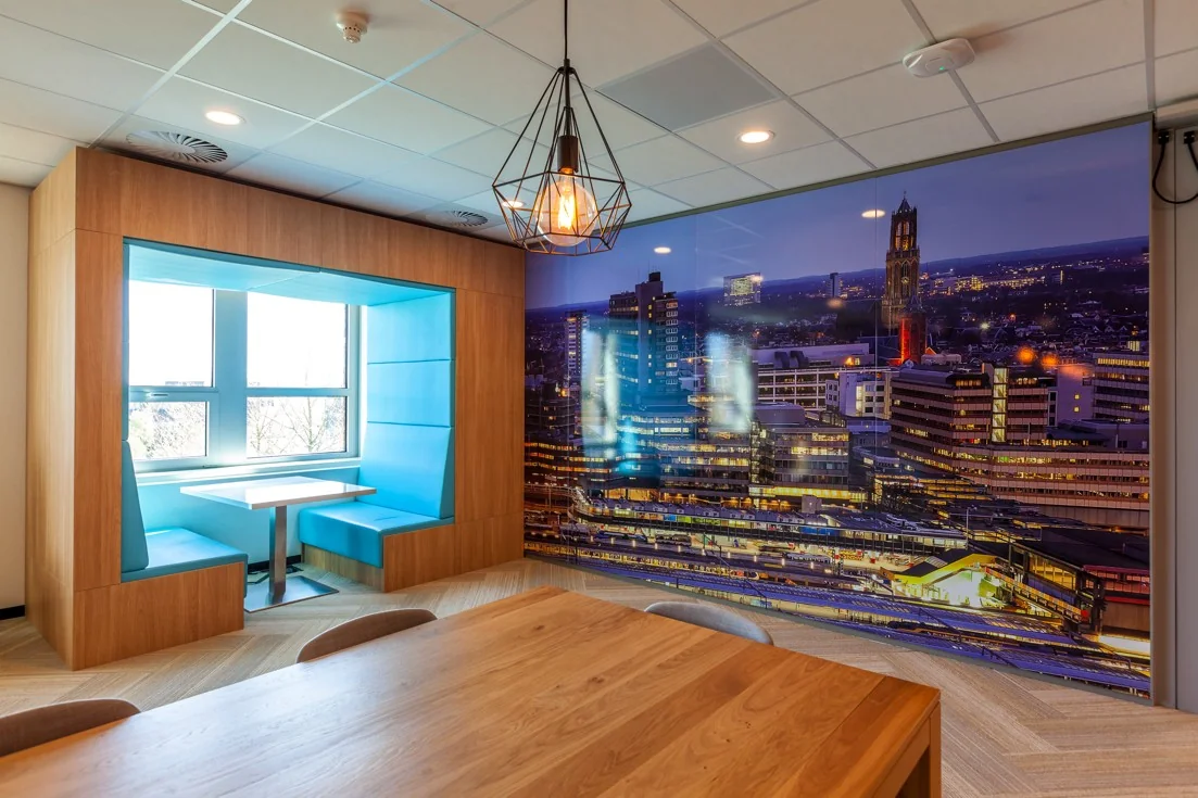 Moderne kantoorruimte met een zitnis in blauw en een muurdecoratie van de skyline van Utrecht bij nacht.