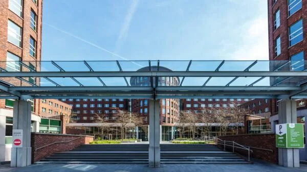 Ingang van het kantoorgebouw aan de Orteliuslaan in Utrecht, omgeven door moderne bakstenen gevels en een glazen loopbrug.