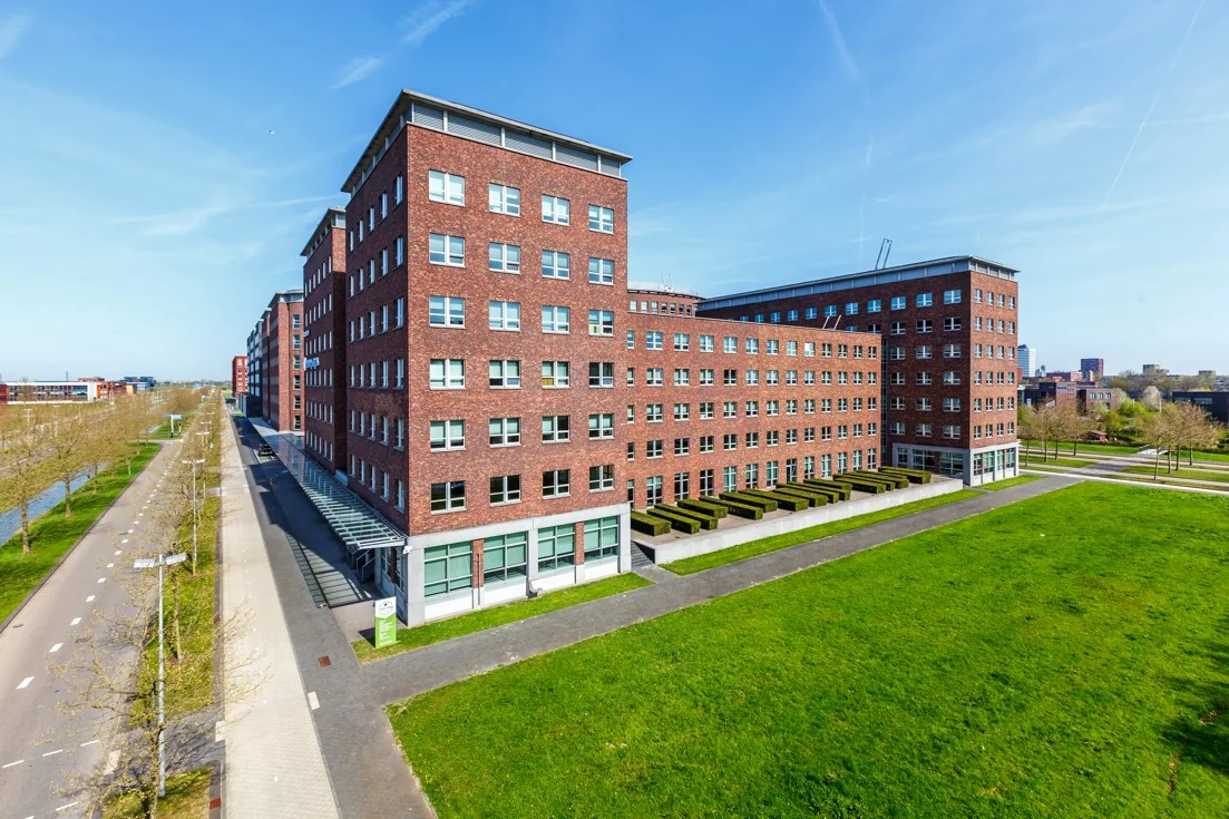 Modern kantoorgebouw aan de Orteliuslaan in Utrecht met roodbruine bakstenen gevel en groene omgeving.