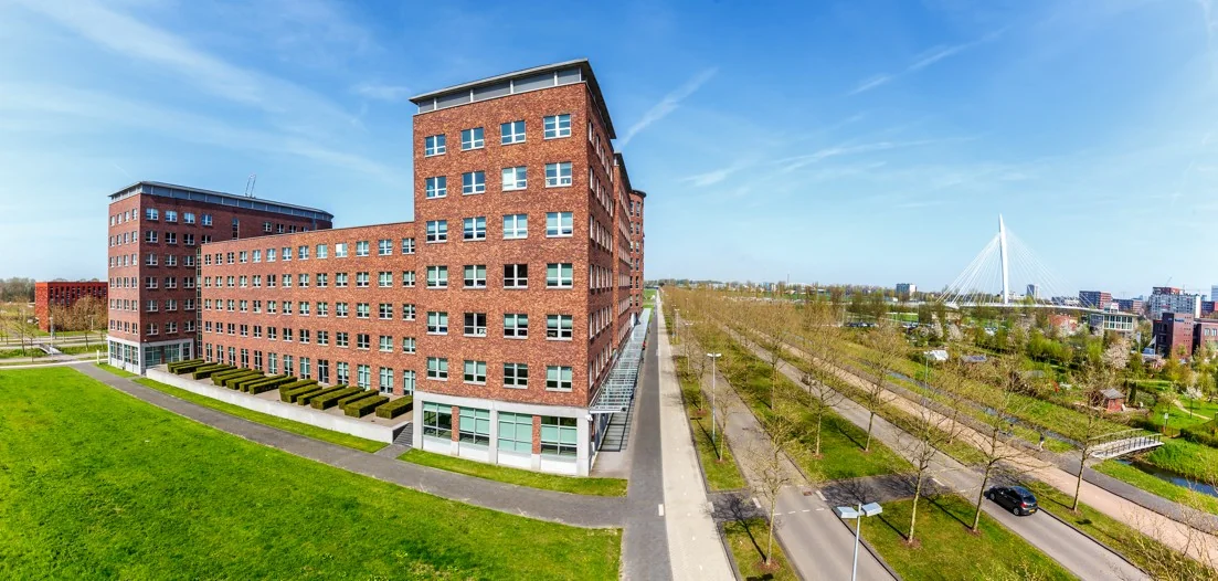 Kantoorgebouw aan de Orteliuslaan in Utrecht met op de achtergrond de Dafne Schippersbrug en een groene stadsomgeving.
