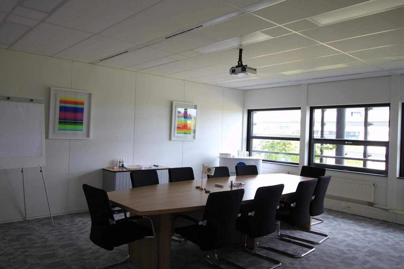 Vergaderzaal aan de Marconibaan met grote tafel, zwarte stoelen, flip-over en plafondbeamer.
