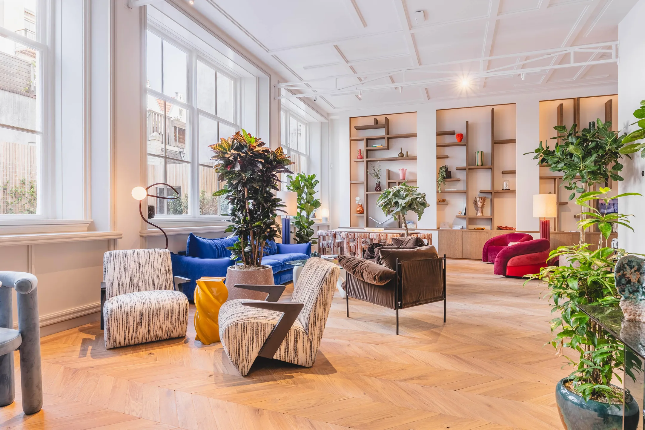 Een stijlvolle, lichte woonkamer met moderne meubels, houten vloer en veel groene planten.