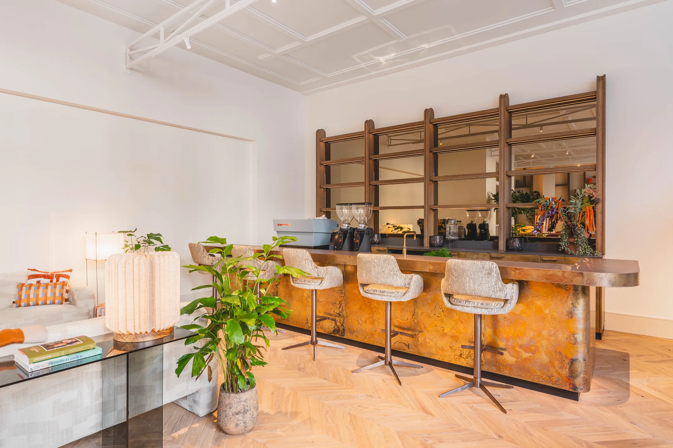 Een moderne interieursetting met een stijlvol ingebouwde bar, comfortabele stoelen en een eigentijdse inrichting met planten en decoratieve elementen.