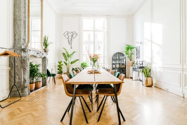 Lichte en stijlvol ingerichte vergaderruimte aan de Herengracht met lange houten tafel, planten en hoge ramen.