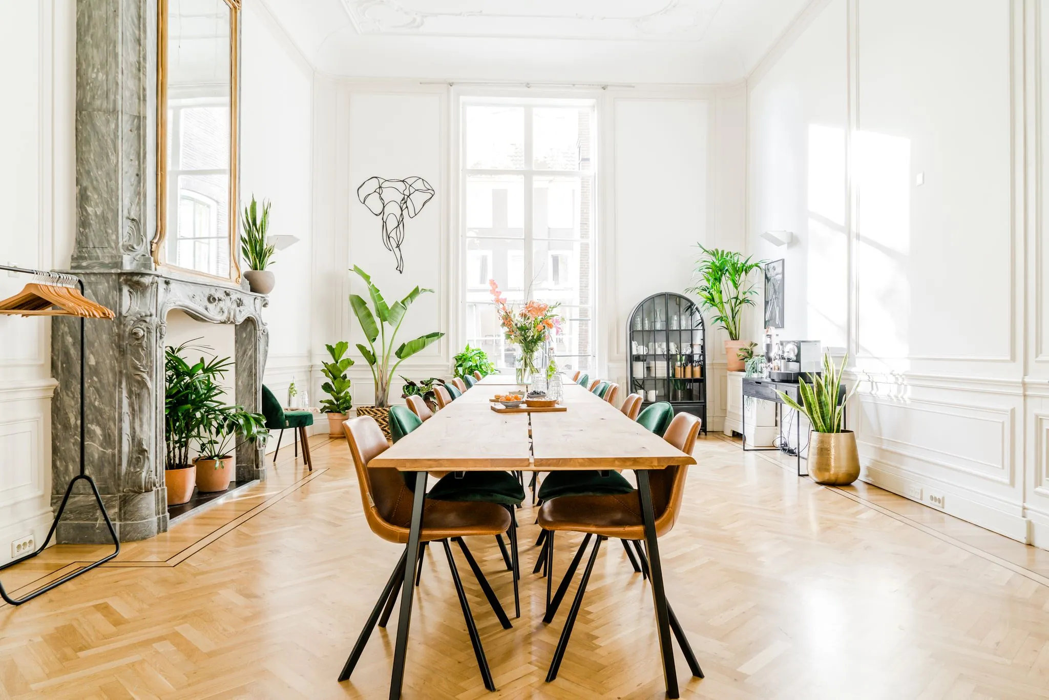 Lichte en stijlvol ingerichte vergaderruimte aan de Herengracht met lange houten tafel, planten en hoge ramen.