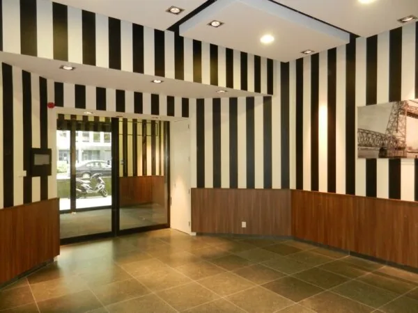 Ingangshal van Westblaak 931 met zwart-wit gestreepte muren, houten lambrisering en glazen toegangsdeur.