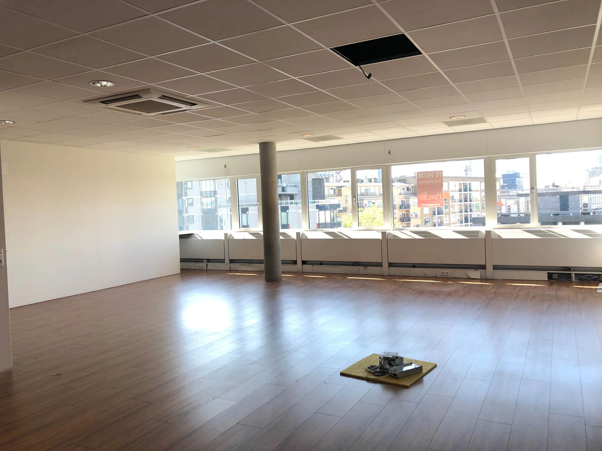 Lichte, lege kantoorruimte aan de Westblaak met houten vloer en grote ramen met uitzicht op de stad.
