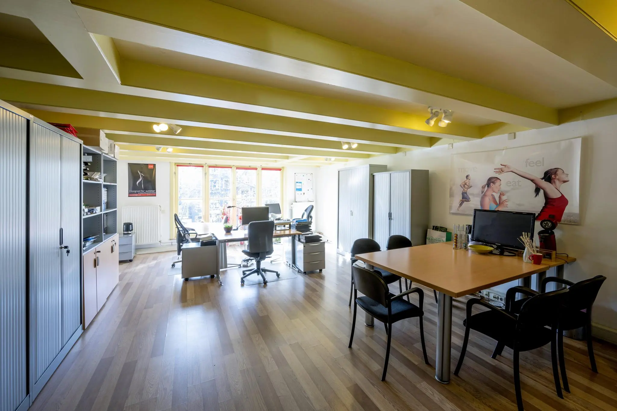 Licht en modern kantoor aan de Leidsegracht met werkplekken, vergadertafel en grote ramen.