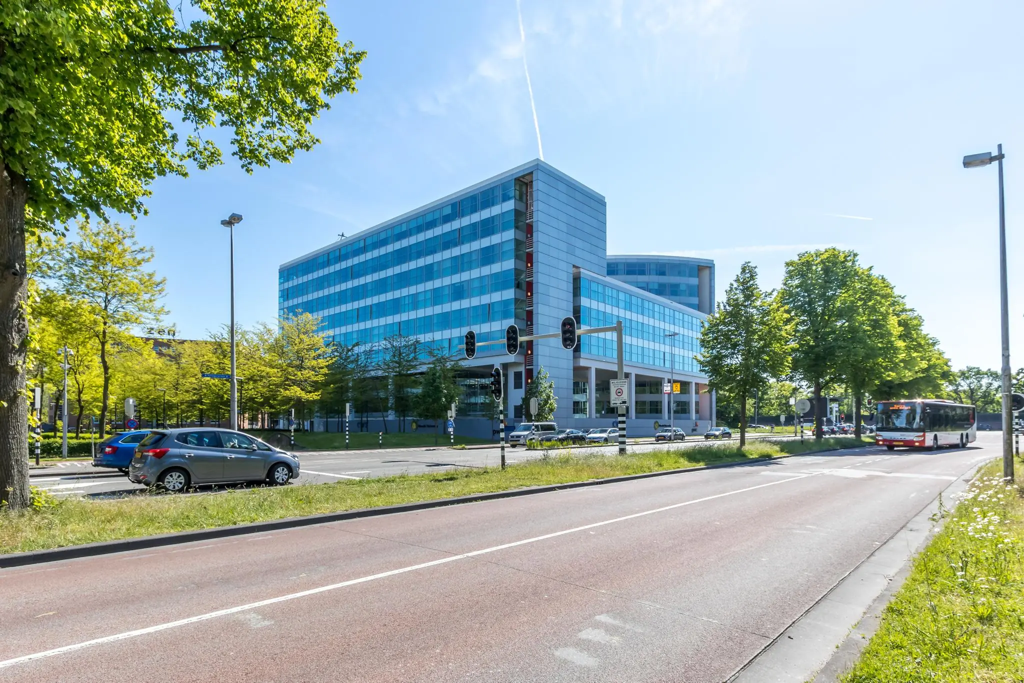 Modern kantoorgebouw aan de Newtonlaan in Utrecht, gezien vanaf de straat met verkeer en openbaar vervoer.