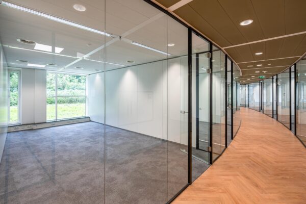 Modern kantoorpand aan de Newtonlaan met glazen wanden, uitzicht op groen en een gang met houten vloer.