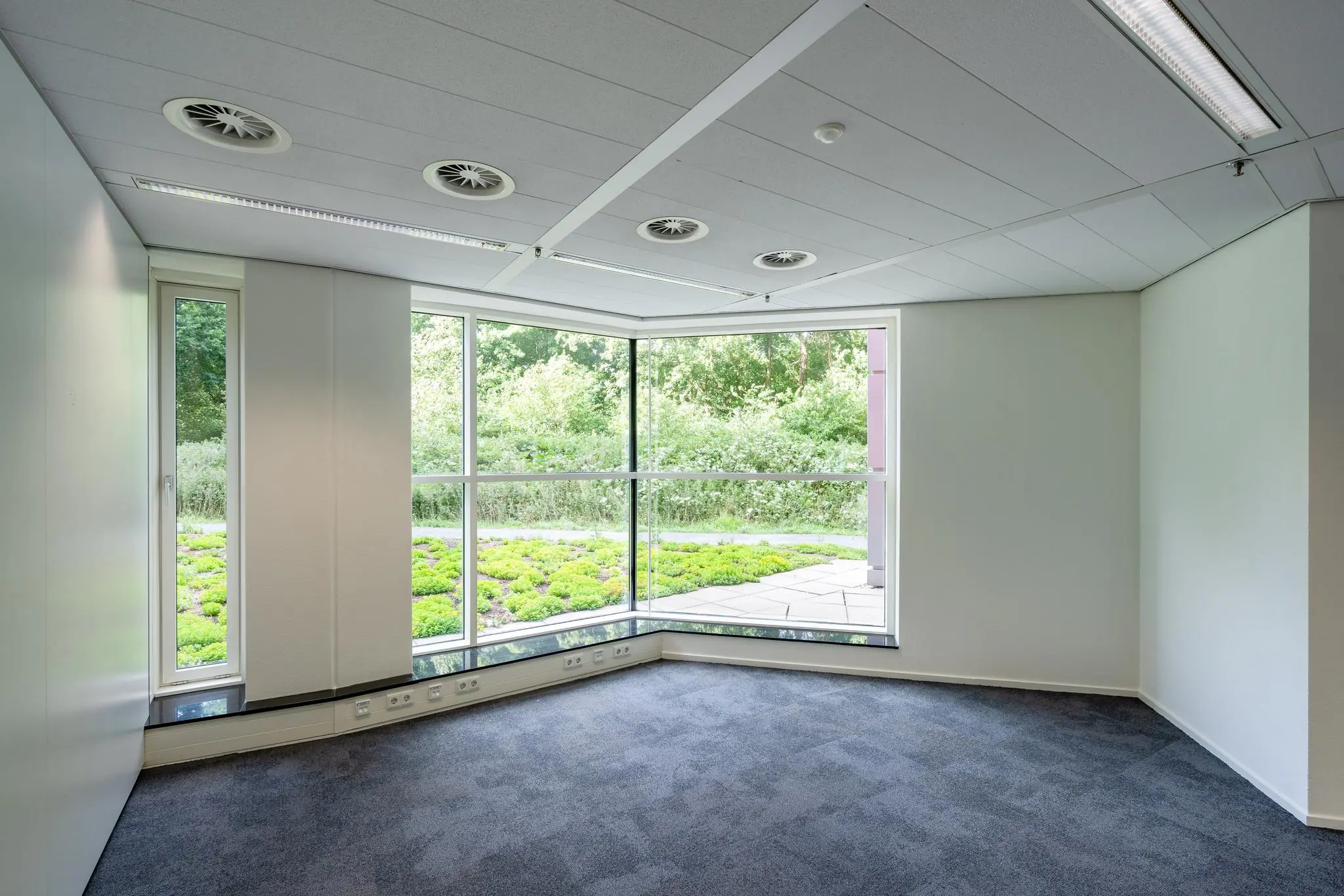Licht kantoorruimte met hoekramen en uitzicht op groen aan de Newtonlaan.