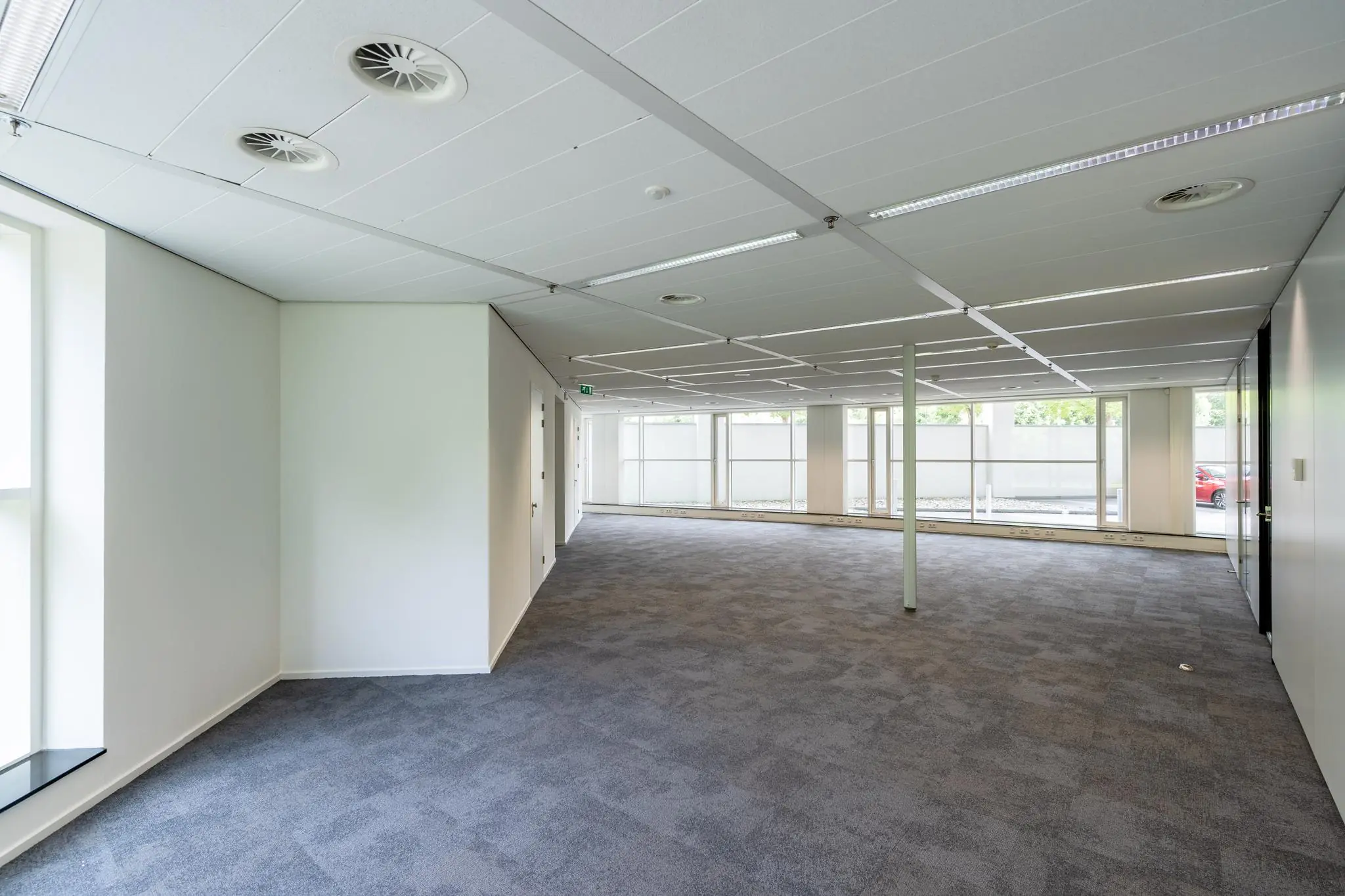 Licht en leeg kantoorpand aan de Newtonlaan met grote ramen en systeemplafond.