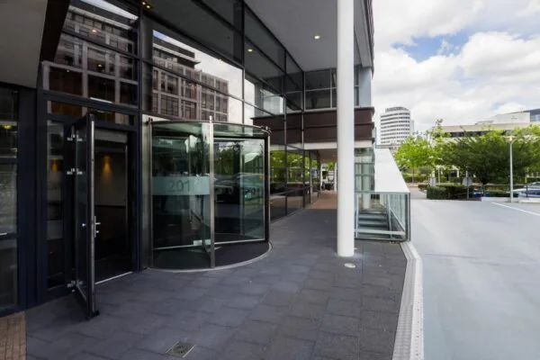 Ingang van een modern kantoorgebouw aan de Euclideslaan met een glazen draaideur en omliggende stadsbebouwing.