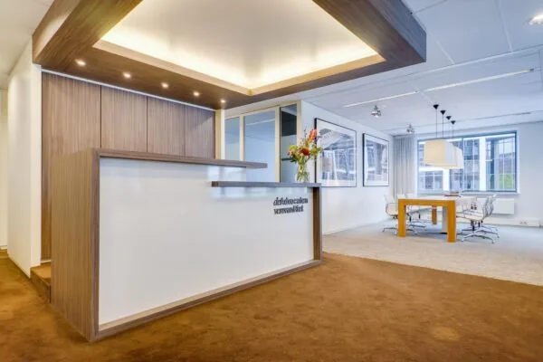 Moderne ontvangstruimte en vergaderruimte van advocatenkantoor aan de Euclideslaan met houten balie en strakke inrichting.