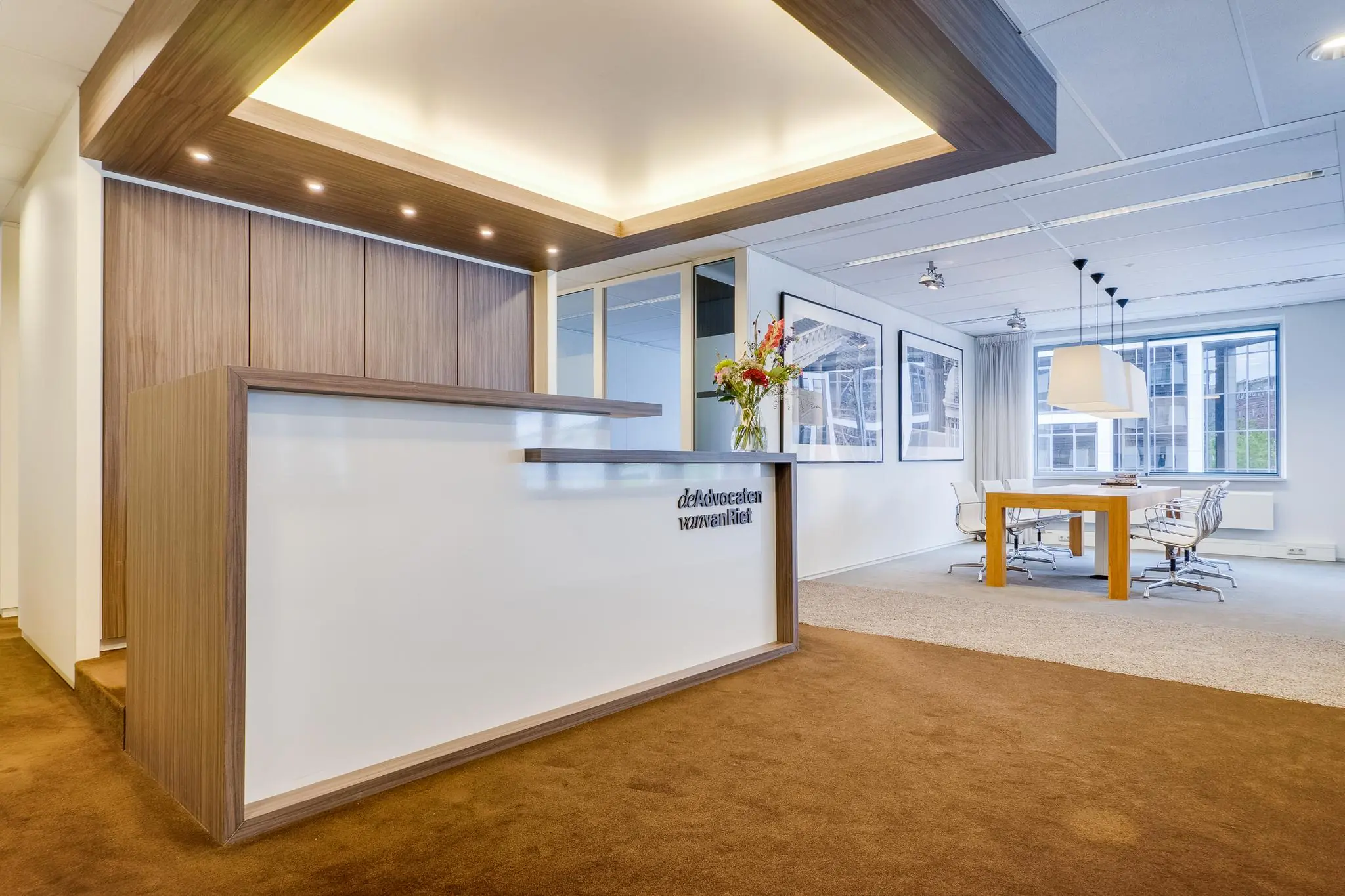 Moderne ontvangstruimte en vergaderruimte van advocatenkantoor aan de Euclideslaan met houten balie en strakke inrichting.