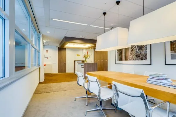Moderne vergaderruimte aan de Euclideslaan met houten tafel, witte stoelen en kunst aan de muur.