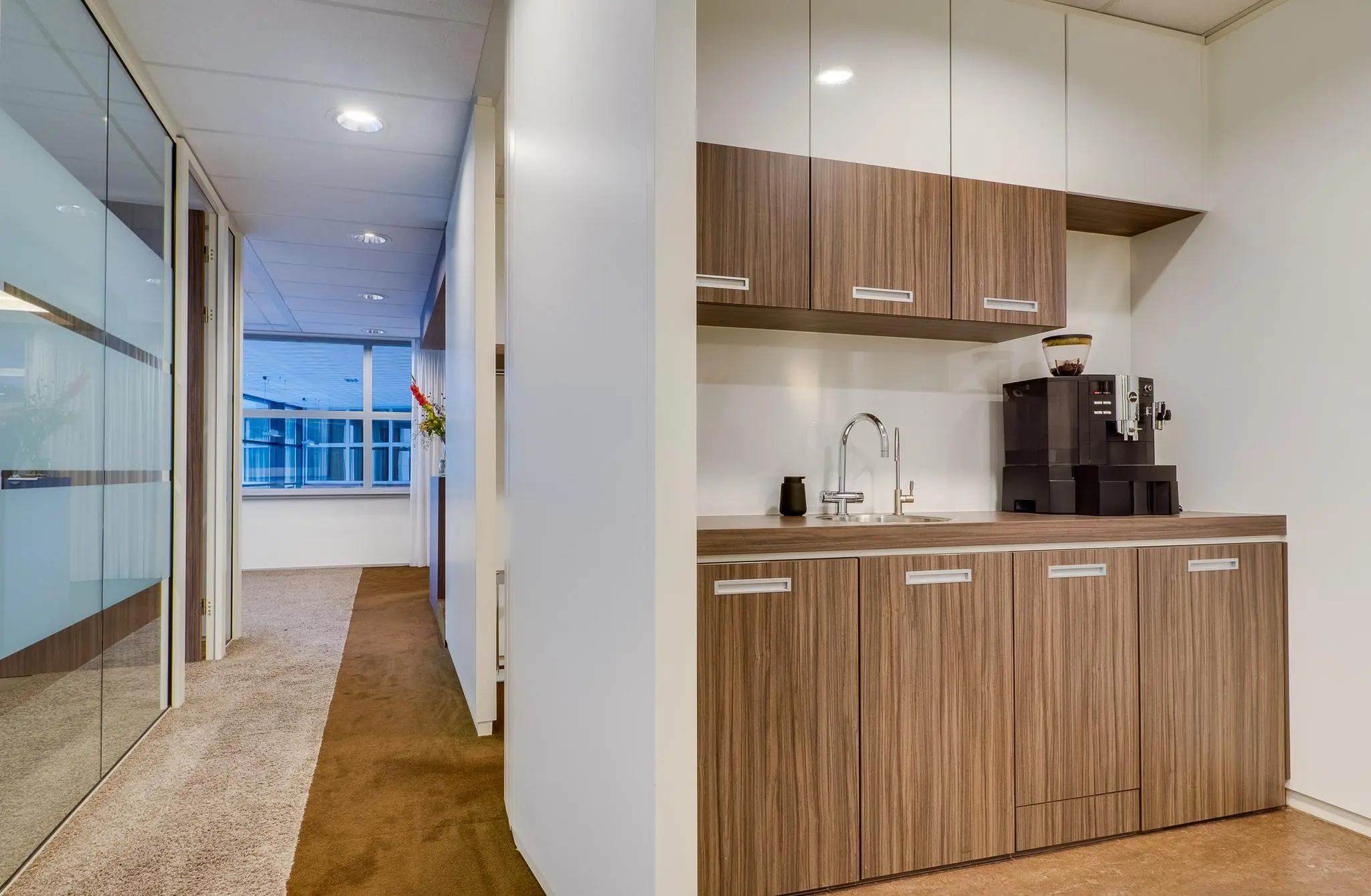 Moderne kantoorpanty met een kitchenette voorzien van een koffieautomaat en houten kastjes aan de Euclideslaan.