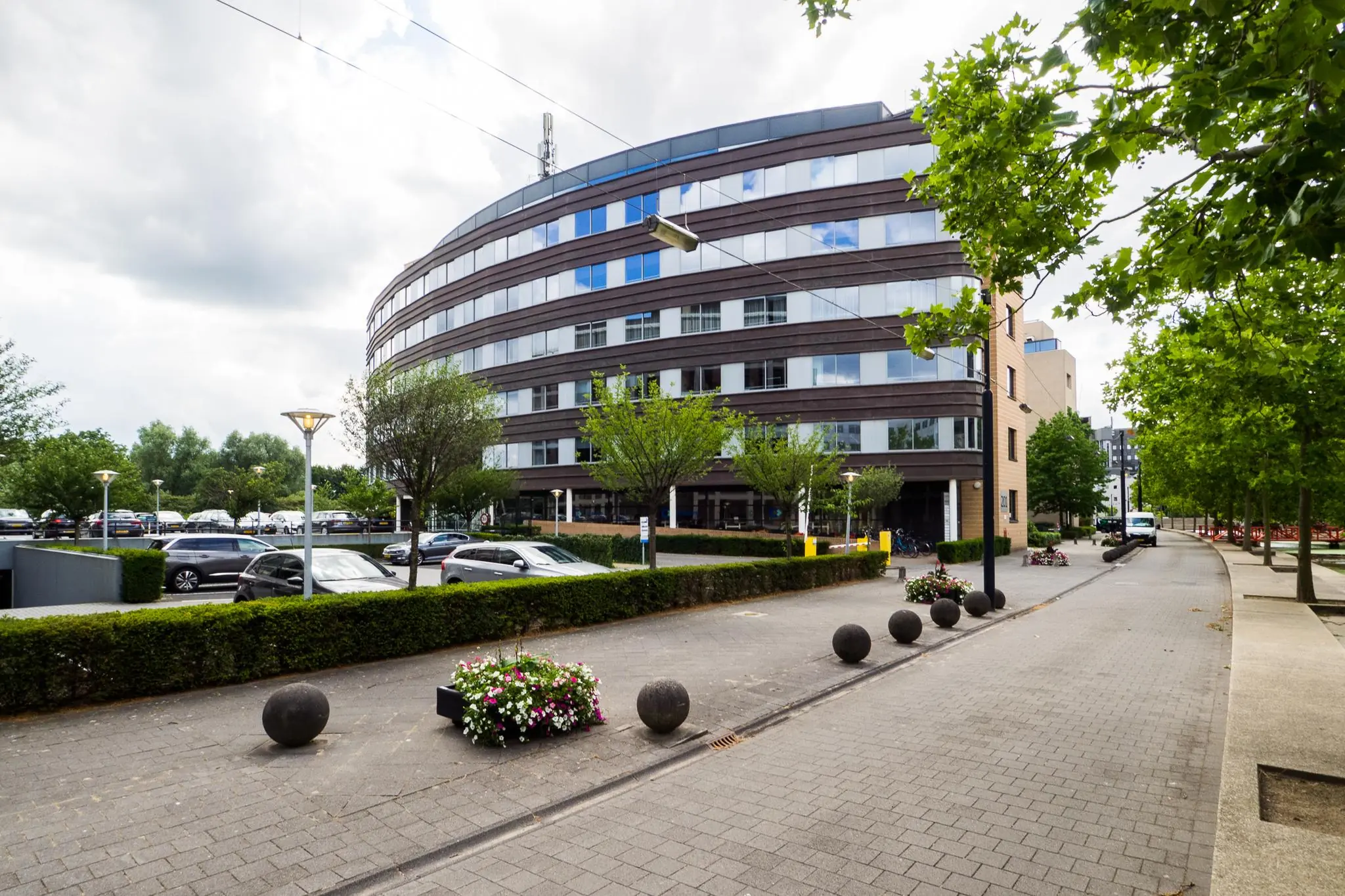 Rond kantoorgebouw aan de Euclideslaan in Utrecht met parkeervoorzieningen en een bomenrijke straat.