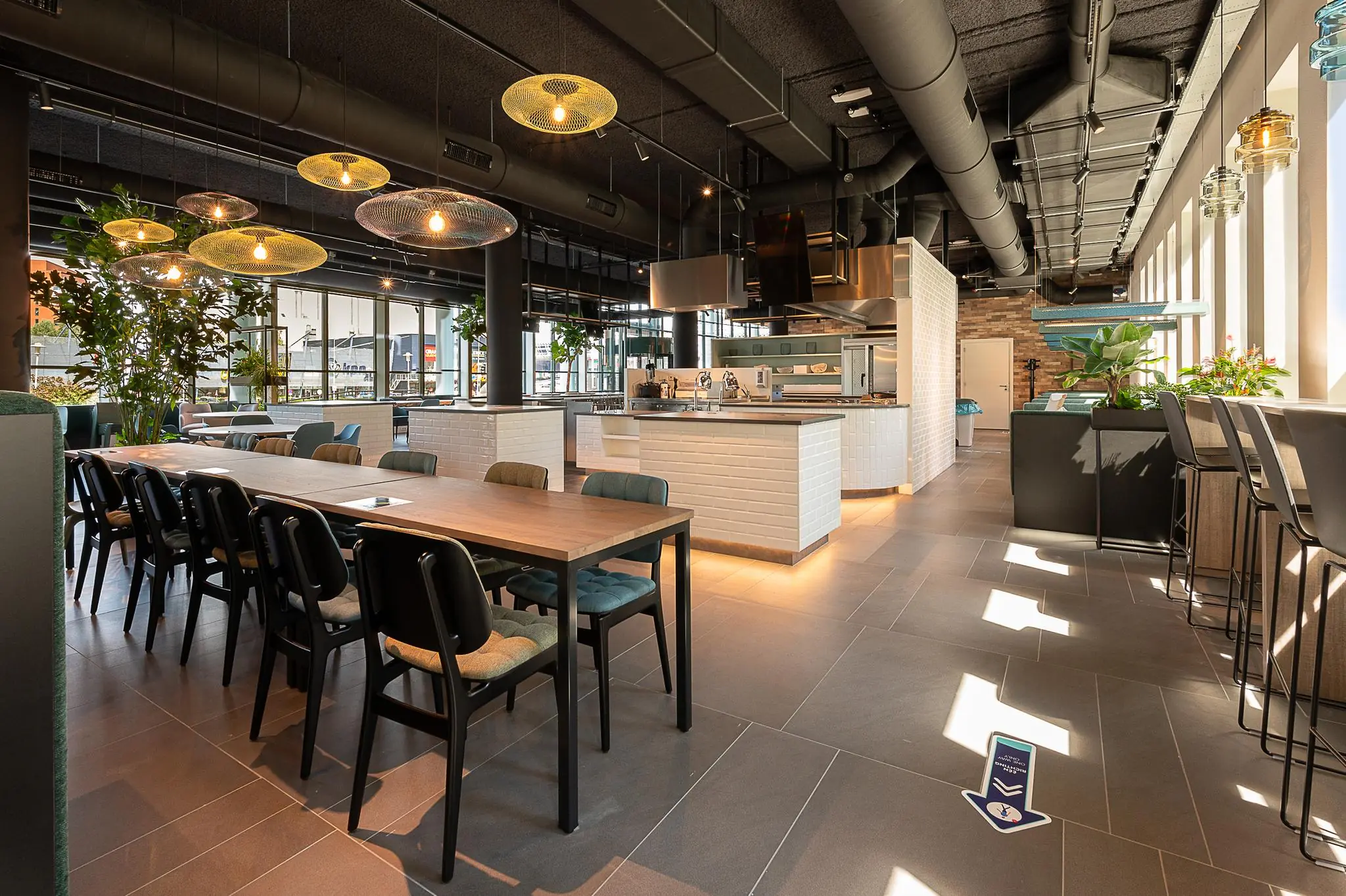 Moderne, open keukenruimte met lange eettafels en stijlvolle verlichting aan de Watermanweg.