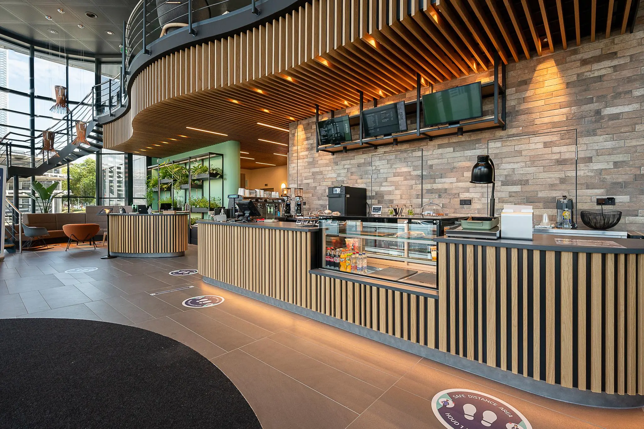Moderne koffiebar met houten accenten en grote ramen in de lobby van een kantoorgebouw aan de Watermanweg.