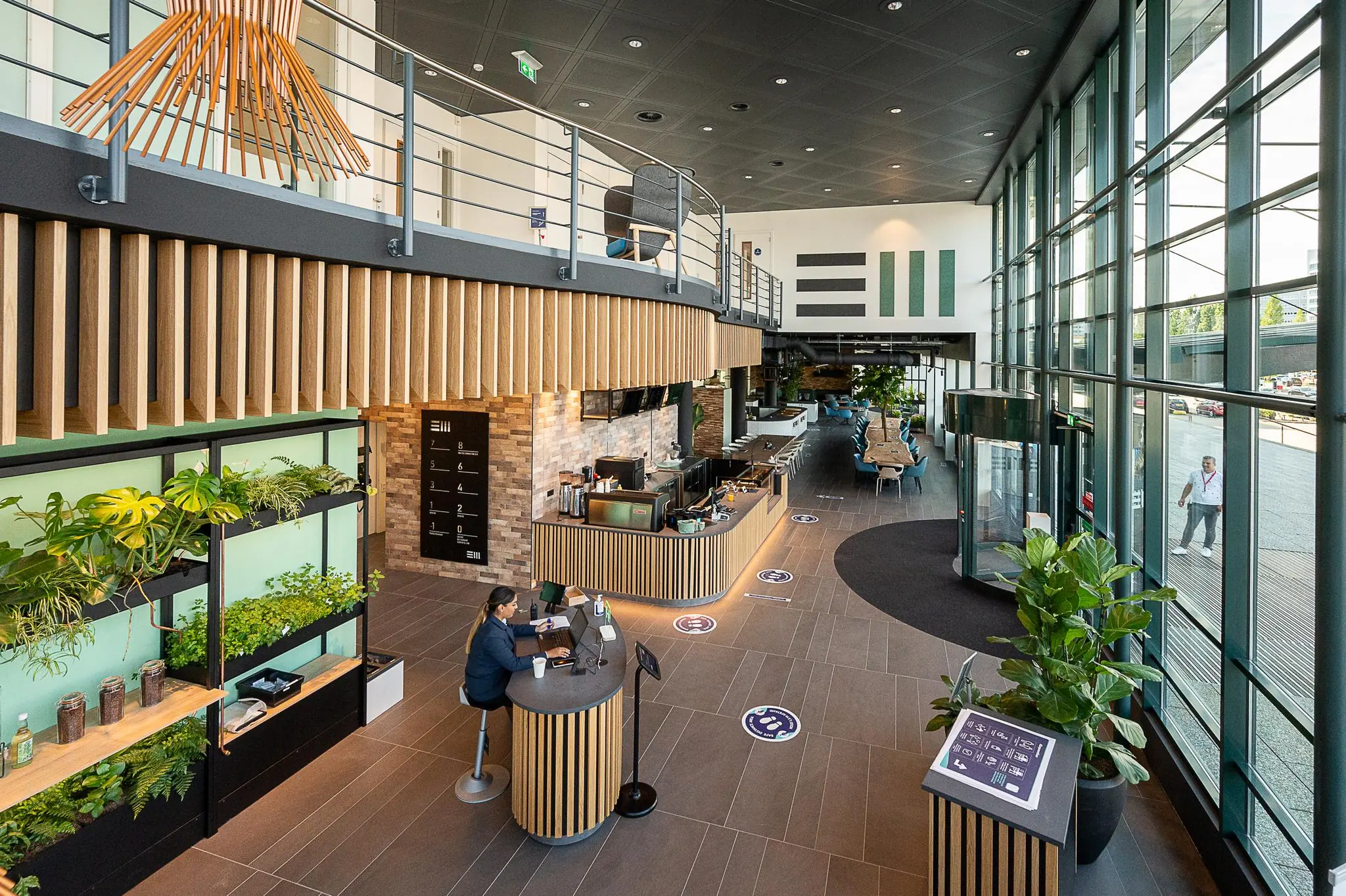 Moderne ontvangsthal aan de Watermanweg met een balie, plantenwand, zitgedeelte en grote glazen gevel.
