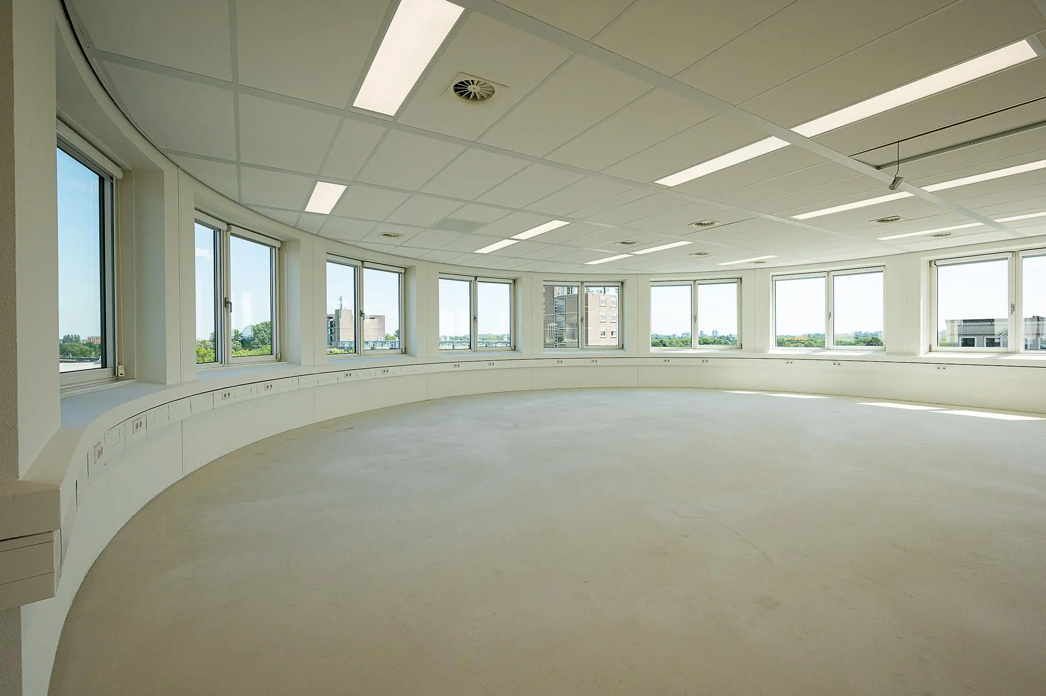 Licht en rond kantoorruimte met grote ramen aan de Watermanweg, met zicht op de stad.