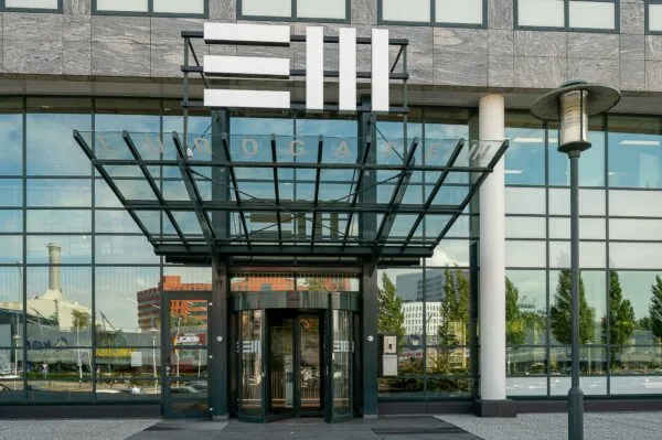 Ingang van het Eurogate-gebouw aan de Watermanweg met glazen overkapping en draaideur.