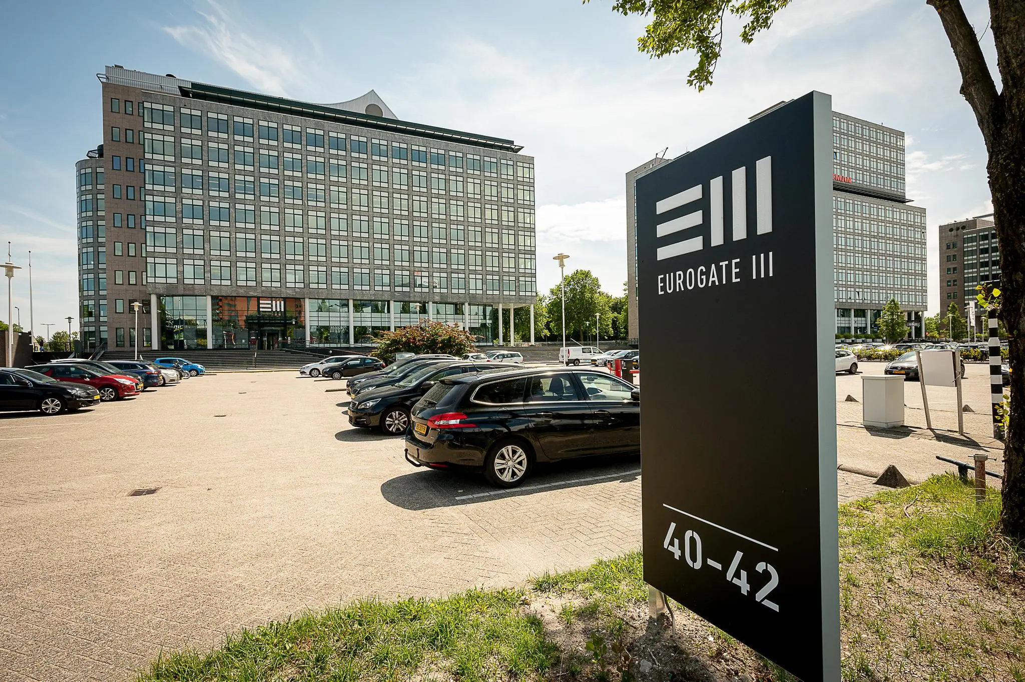 Kantoorgebouw Eurogate III aan de Watermanweg 40-42 met parkeerterrein op de voorgrond.